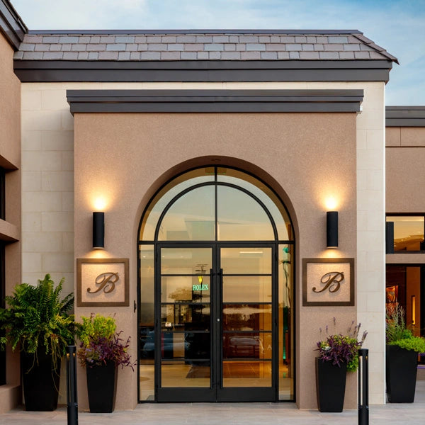 Blakemans Jewelry store exterior with arched glass entrance, decorative B panels, potted plants, and visitor information including address and hours in Rogers, Arkansas.